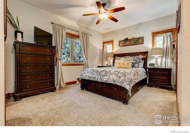 bedroom featuring light carpet, a ceiling fan, and baseboards