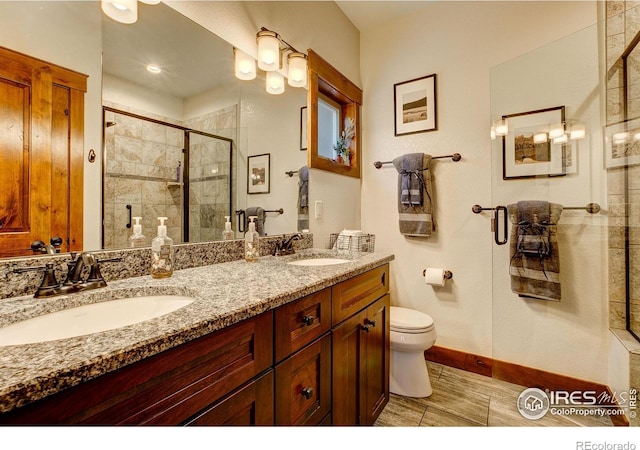 full bathroom featuring double vanity, a stall shower, toilet, and a sink