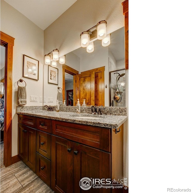 bathroom featuring a sink, a shower, wood finished floors, and double vanity