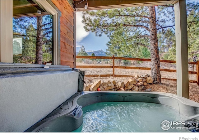 view of swimming pool featuring a hot tub and fence