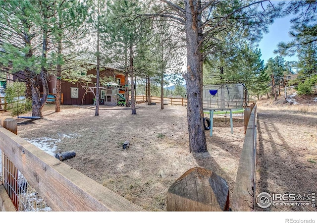 view of yard with playground community, a trampoline, and fence