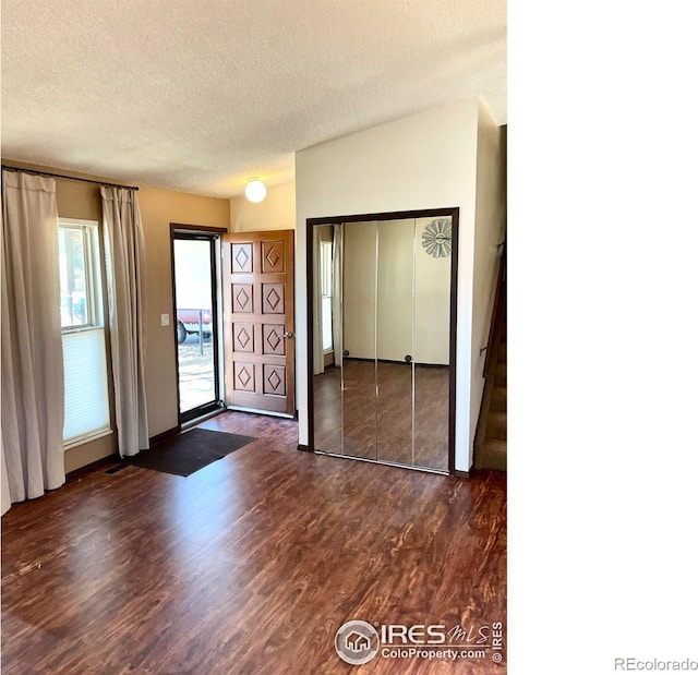 interior space with access to exterior, a textured ceiling, a closet, and dark wood-style flooring