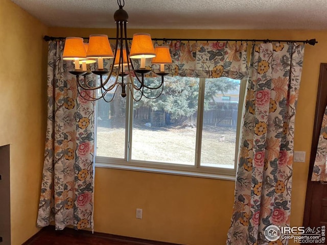 unfurnished dining area with a chandelier and a textured ceiling