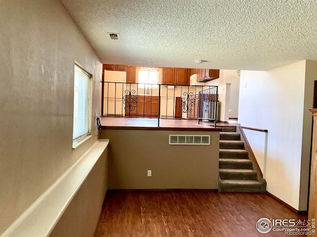 interior space with visible vents, a textured ceiling, baseboards, and wood finished floors