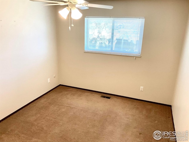 carpeted spare room with baseboards, visible vents, and ceiling fan