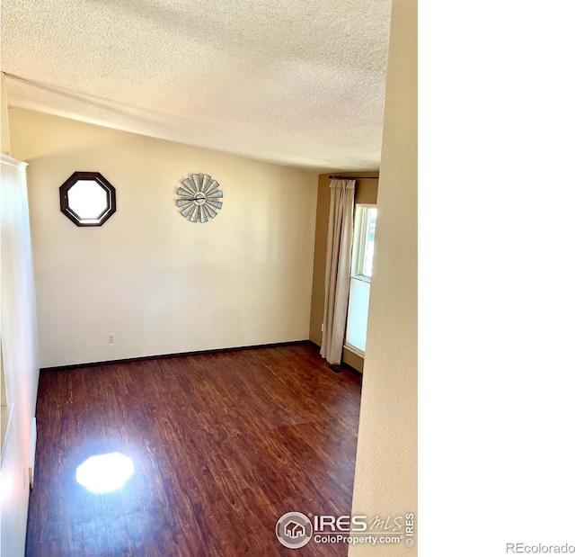 empty room with a textured ceiling and dark wood-type flooring