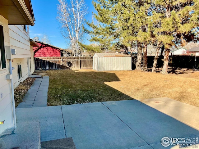 view of yard with an outbuilding, a fenced backyard, a shed, and a patio area