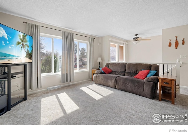 living room with visible vents, carpet flooring, a textured ceiling, and a ceiling fan