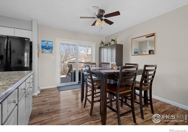 dining area featuring baseboards, a textured ceiling, ceiling fan, and wood finished floors