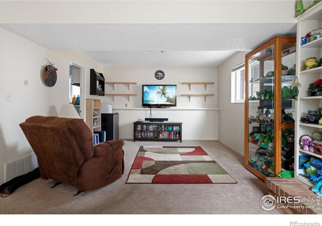 living area featuring visible vents, carpet floors, and a textured ceiling