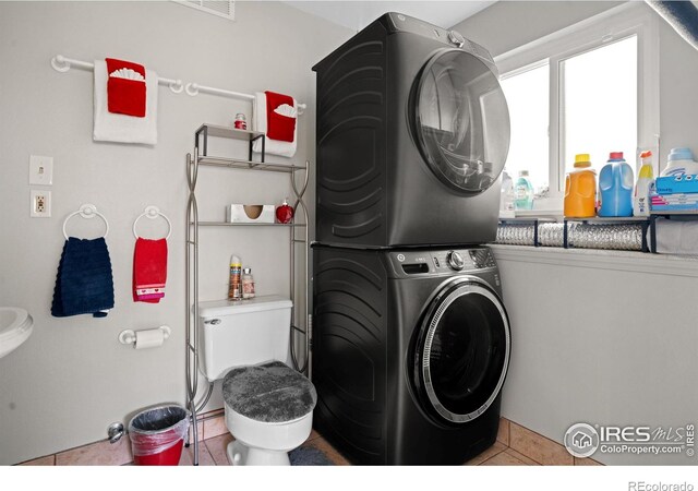 laundry area featuring tile patterned flooring, laundry area, and stacked washer and dryer