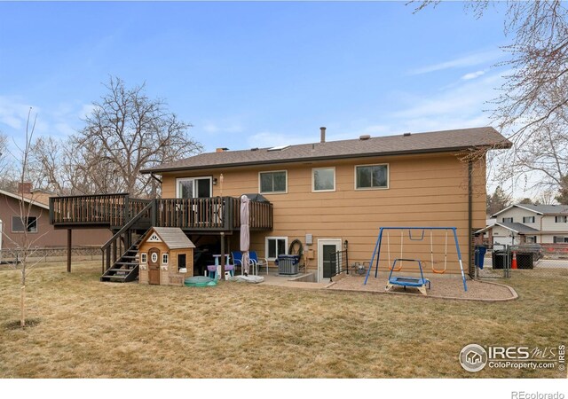 back of property with a playground, a yard, and fence