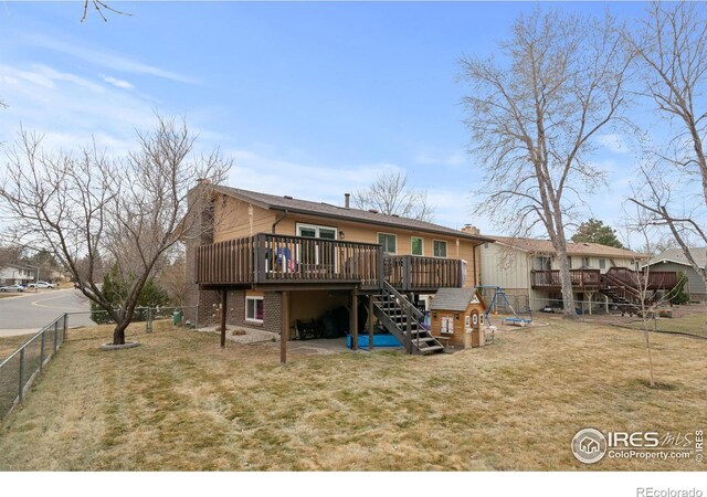 back of property featuring a wooden deck, stairs, a lawn, a chimney, and a fenced backyard