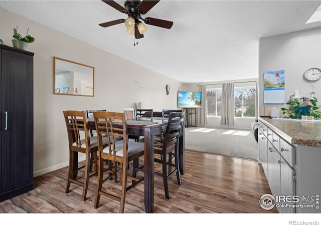 dining room featuring a textured ceiling, wood finished floors, baseboards, and ceiling fan