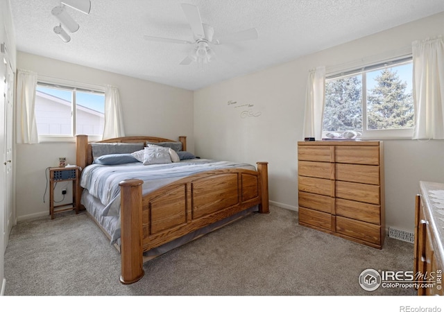 bedroom with a ceiling fan, baseboards, visible vents, a textured ceiling, and light colored carpet