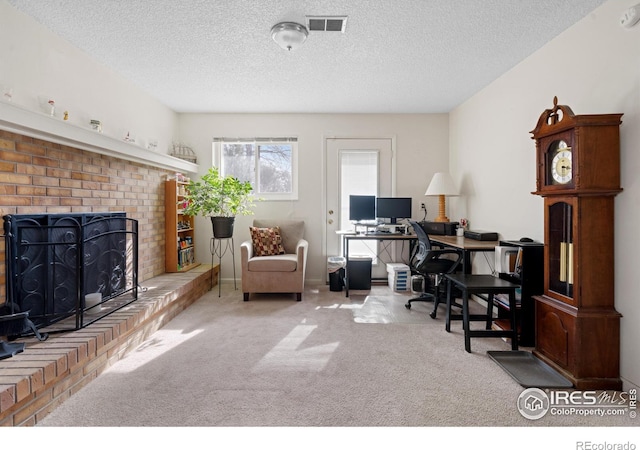 carpeted office space with visible vents, a textured ceiling, and a fireplace