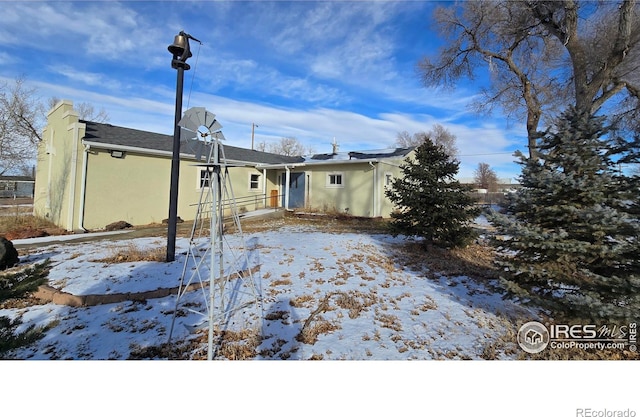 snow covered house featuring stucco siding