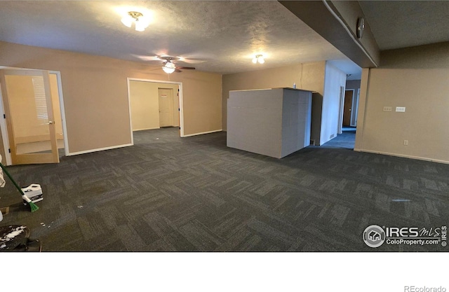 unfurnished living room featuring baseboards, a ceiling fan, and dark carpet