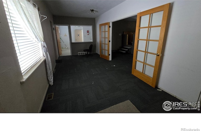 carpeted spare room featuring french doors, visible vents, and baseboards