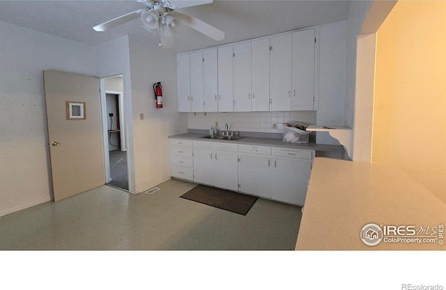 kitchen with a sink, backsplash, white cabinets, light countertops, and ceiling fan