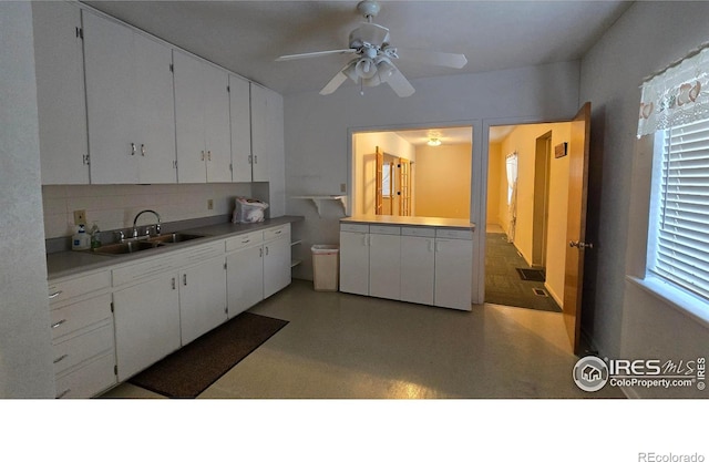 kitchen featuring a sink, white cabinetry, light countertops, decorative backsplash, and ceiling fan