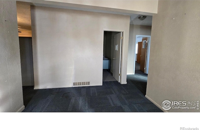 unfurnished room with baseboards, visible vents, and dark colored carpet