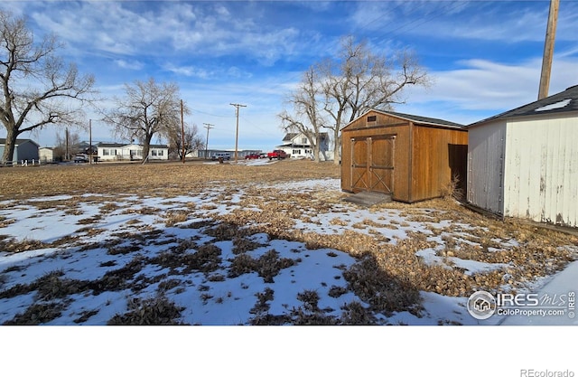 yard layered in snow with a storage unit and an outbuilding