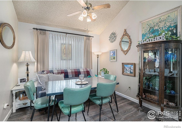 dining space featuring lofted ceiling, a textured ceiling, wood finished floors, baseboards, and ceiling fan