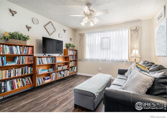 living room featuring a ceiling fan, wood finished floors, baseboards, and a textured ceiling