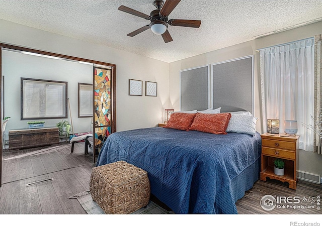 bedroom with ceiling fan, wood finished floors, visible vents, and a textured ceiling