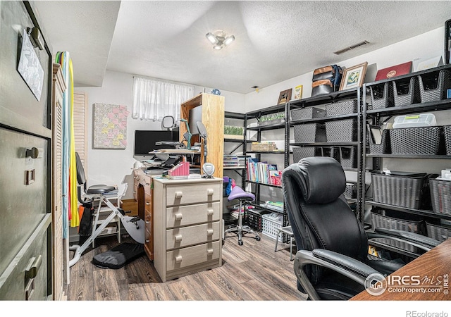 home office featuring visible vents, a textured ceiling, and wood finished floors