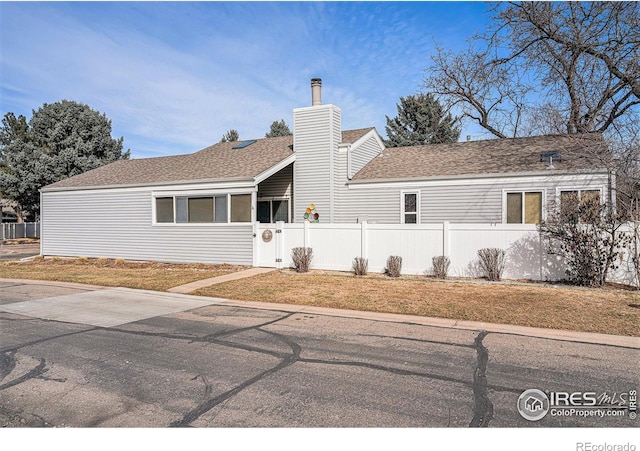 single story home featuring a fenced front yard, a chimney, and a shingled roof