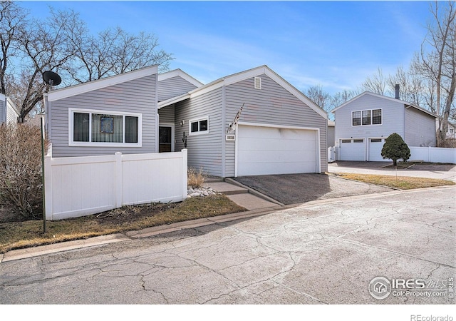 view of front facade with driveway, a garage, and fence