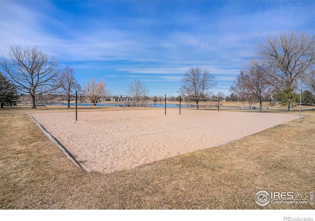 view of home's community with a yard, volleyball court, and a water view