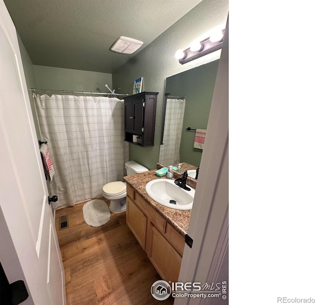 full bathroom featuring visible vents, wood finished floors, vanity, a textured wall, and a textured ceiling