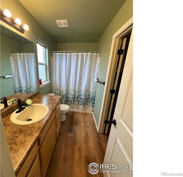 bathroom featuring a shower with curtain, toilet, wood finished floors, and vanity