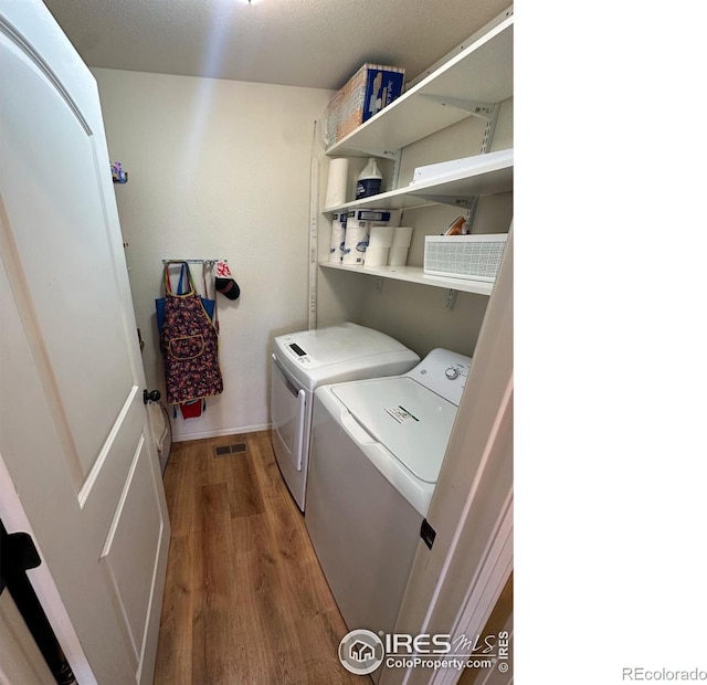 laundry area featuring washer and dryer, laundry area, wood finished floors, and visible vents