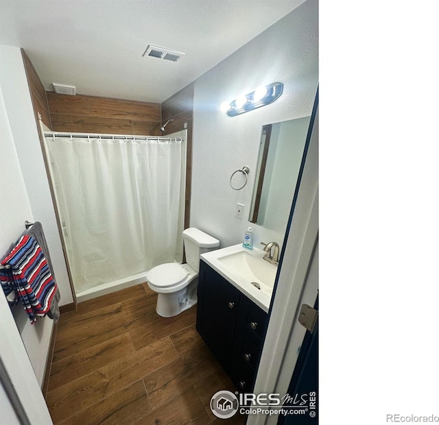 full bath featuring visible vents, vanity, a shower with curtain, and wood finished floors