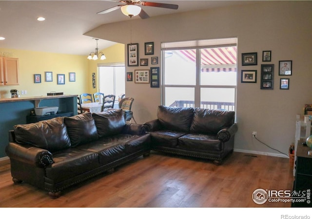 living area featuring lofted ceiling, ceiling fan with notable chandelier, wood finished floors, recessed lighting, and baseboards