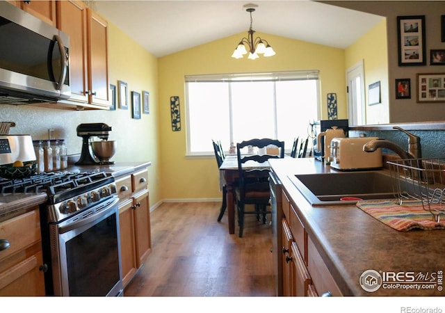 kitchen featuring dark countertops, brown cabinets, stainless steel appliances, and a sink