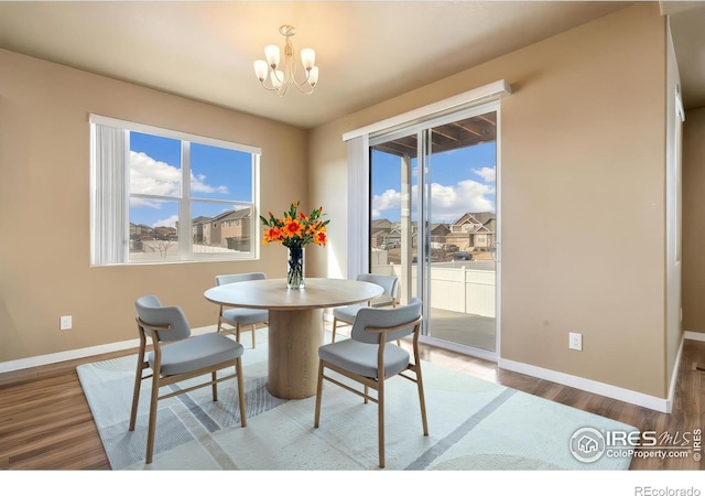 dining space with an inviting chandelier, wood finished floors, and baseboards