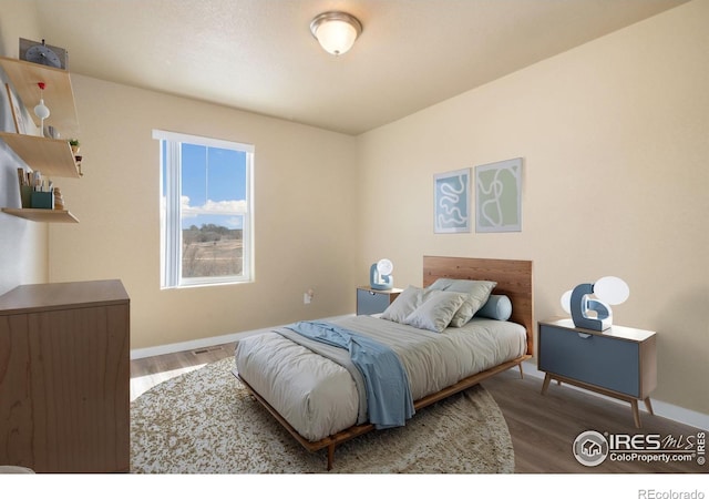 bedroom with baseboards and wood finished floors