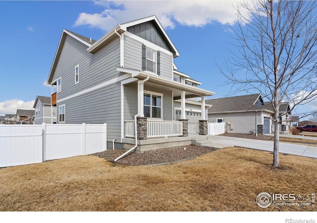 craftsman-style house featuring covered porch, board and batten siding, a front yard, and fence