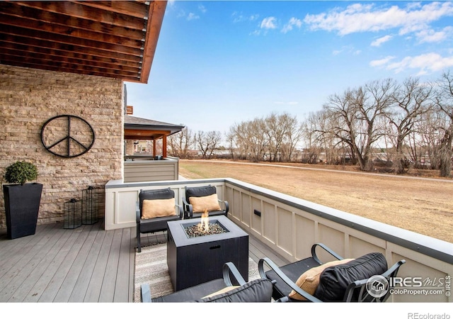 wooden deck featuring a fire pit and a lawn