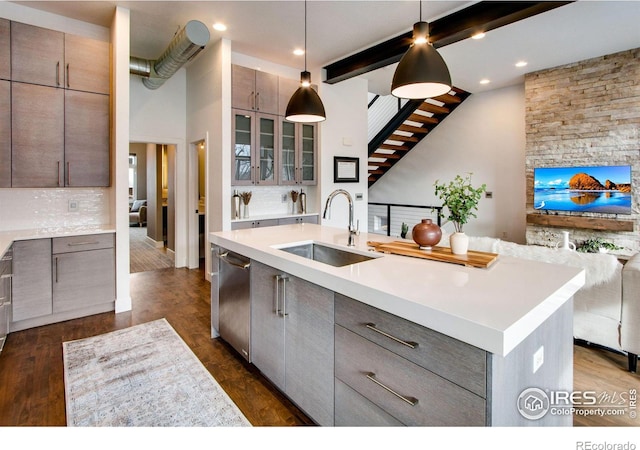 kitchen featuring a sink, backsplash, gray cabinetry, and dishwasher