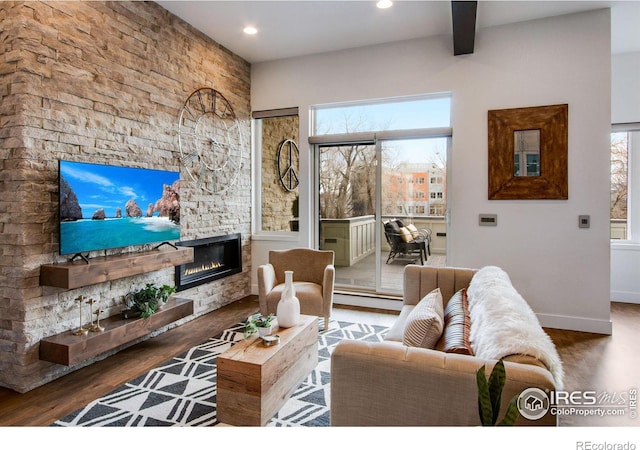 living area with a wealth of natural light, a glass covered fireplace, recessed lighting, and wood finished floors