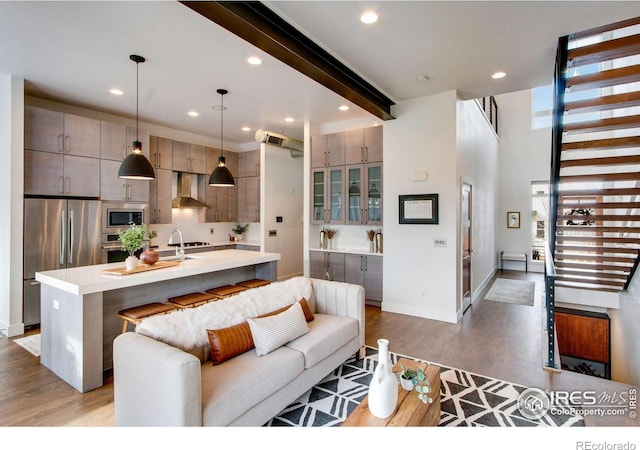 living room featuring beam ceiling, recessed lighting, stairs, and light wood-style floors