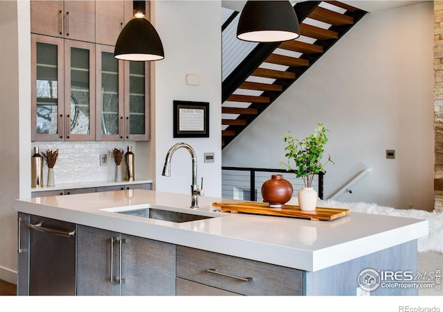 kitchen with a sink, glass insert cabinets, gray cabinets, and light countertops