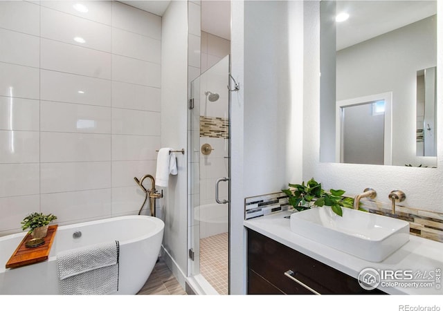 bathroom featuring vanity, a freestanding bath, tile walls, and a shower stall