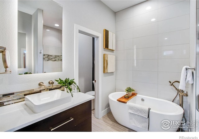 bathroom with vanity, tile walls, and a freestanding tub